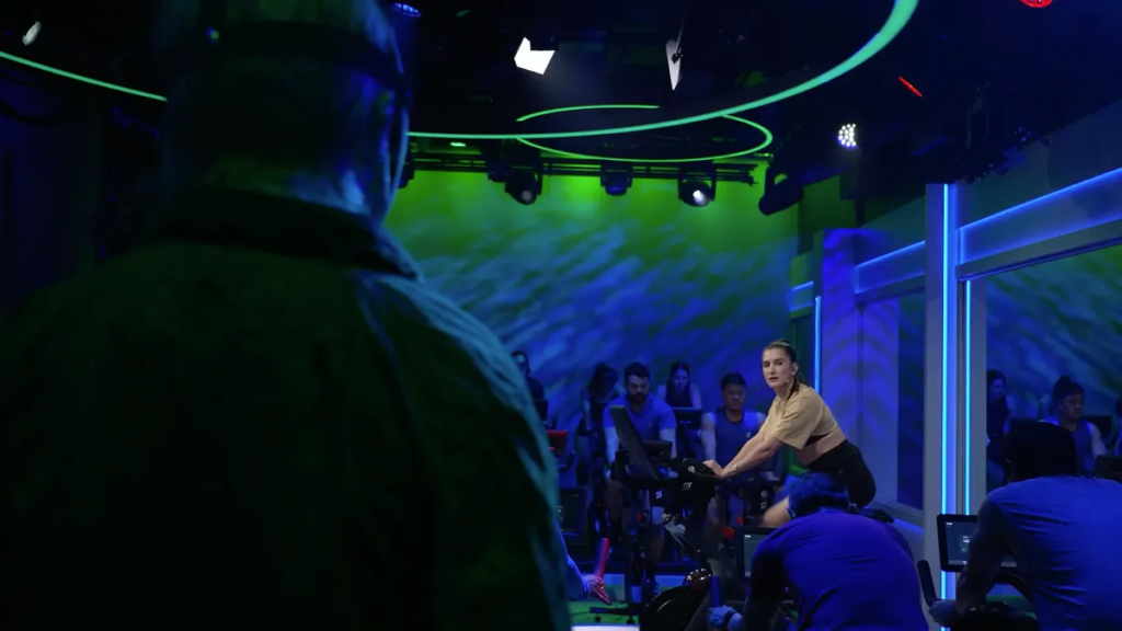 Peloton’s Friday the 13th-Themed Workouts Let You Try to Escape Jason, the Iconic Killer Peloton instructor peers at a masked killer as she cycles away on her exercise bike.