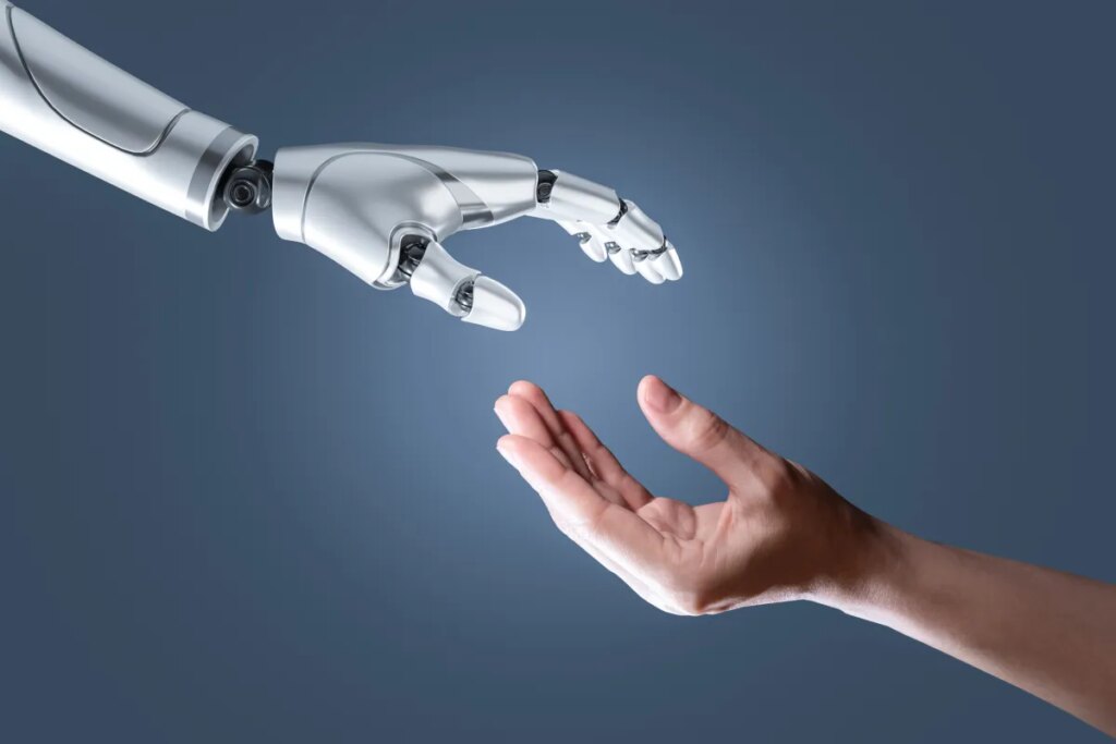 The world is just not quite ready for humanoids yet image of a humanoid hand reaching out to a human hand