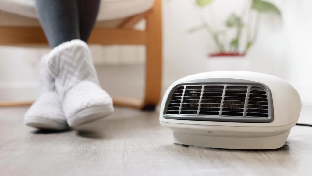 9 Ways You’re Using Your Space Heater Wrong, and Why It Causes Fires A person in warm boots sits in front of a space heater on the ground.
