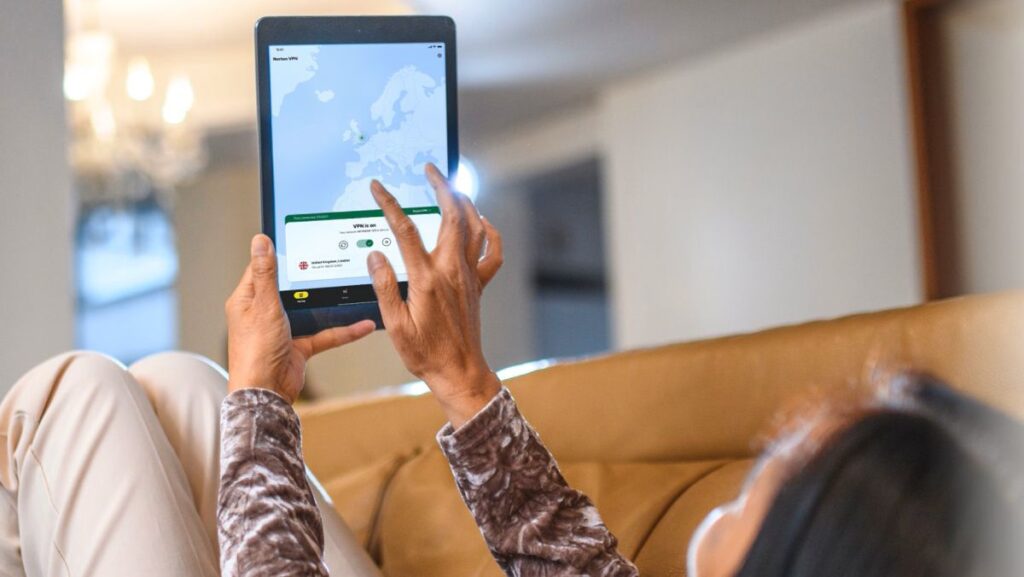 A woman laying back on a sofa and using Norton VPN on her tablet.
