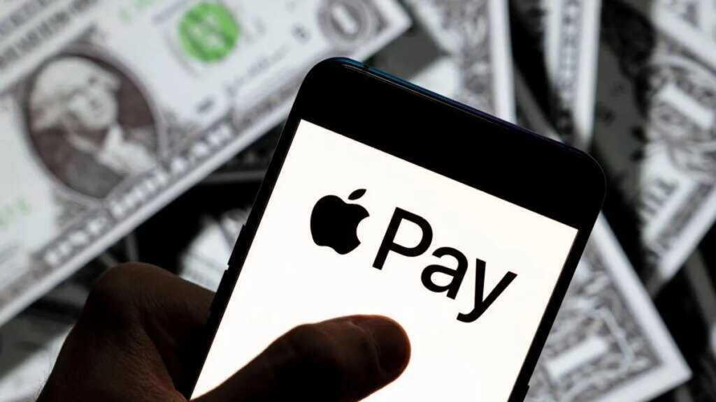 Apple Update Frees Families From Sharing Only 1 Payment Option A phone with an Apple Pay logo held over American dollar bills.