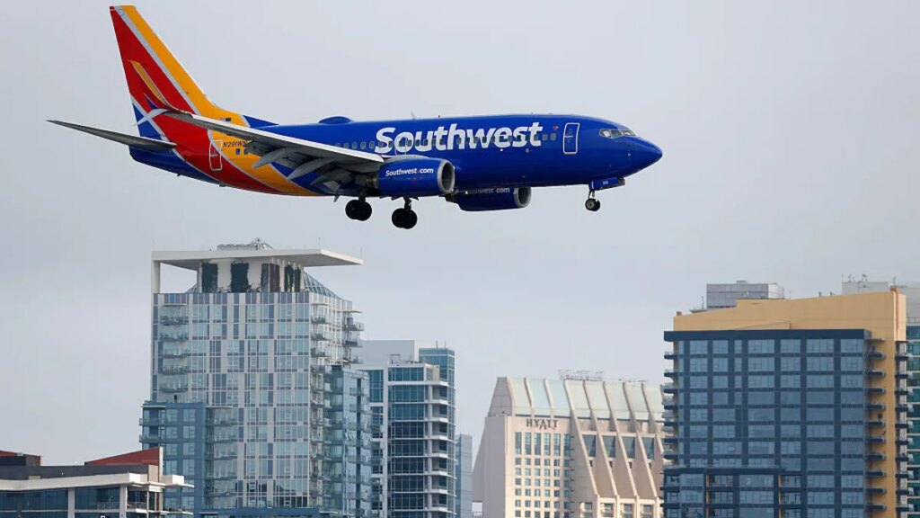 A Southwest Airlines plane in the air with a city skyline in the background