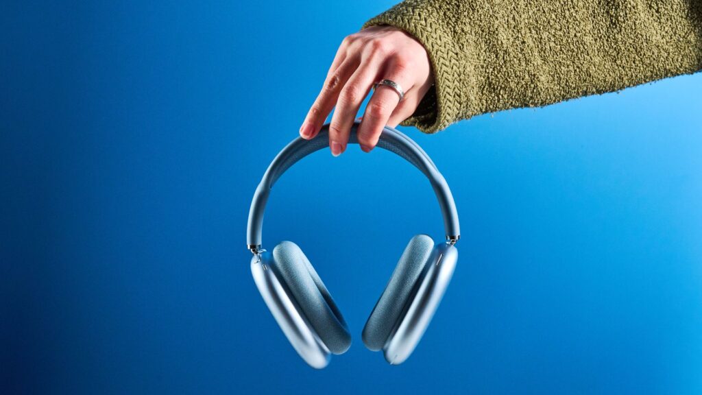 I thought the Apple AirPods Max 2 were way overhyped, but I finally tried them and they’re some of the best headphones I’ve ever used the apple airpods max 2 in blue photographed against a blue tom's guide background, showing the mesh headband, anodized aluminum ear cups, carry case, and controls