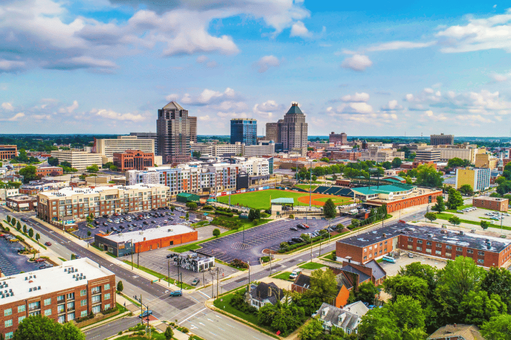 Aerial view of downtown Greensboro, North Carolina, featuring the city skyline, baseball stadium, commercial buildings, and surrounding neighborhoods. New Lumbee website explains upcoming tribal gaming amendment vote before June