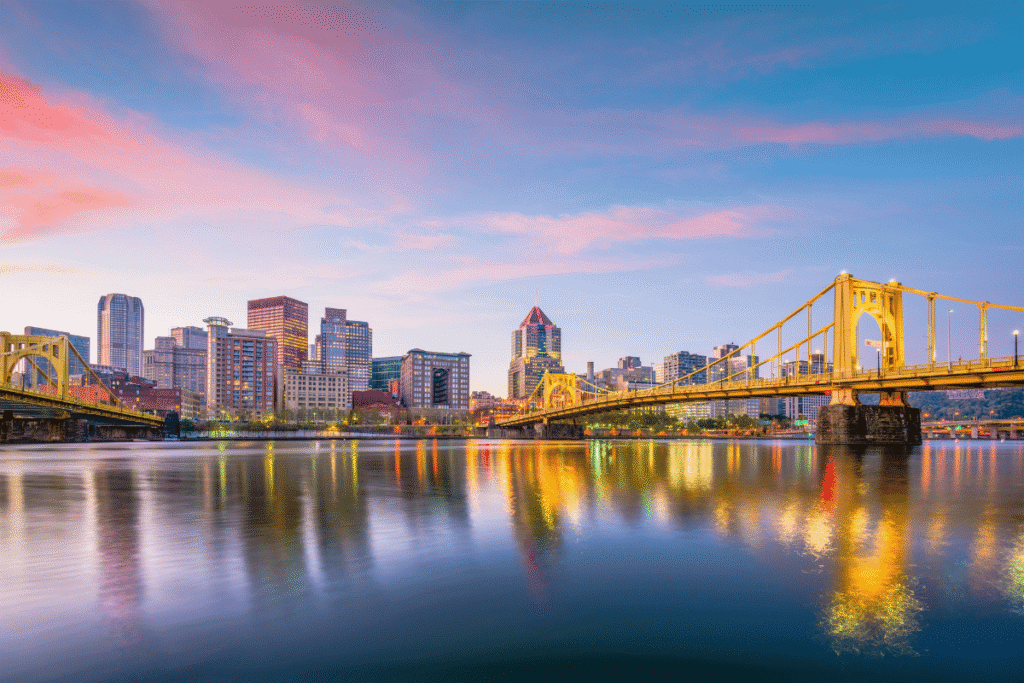 Pennsylvania gaming board issues $180K in enforcement fines Pittsburgh skyline at sunset with illuminated yellow bridges reflecting across the Allegheny River in downtown Pennsylvania. Pennsylvania regulators approve $180K in gaming fines while expanding involuntary exclusion lists