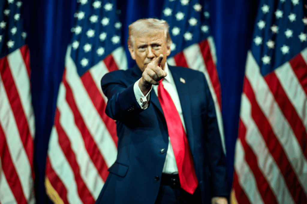 Trump pushes prediction markets over state regulators Donald Trump points during campaign-style appearance surrounded by American flags amid debate over prediction markets and CFTC regulation.