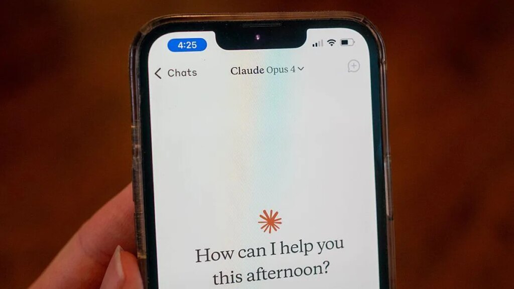 Anthropic Sued Over Alleged False Advertising on Claude Max Subscription Usage Limits A woman holds up a phone with the Claude Opus 4 AI model running. The screen shows the Claude icon and reads, "How can I help you this afternoon?"