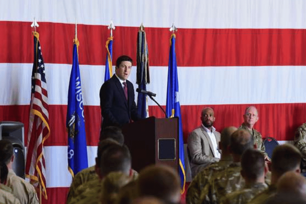 Steil introduces bill restricting congressional prediction market trades. Rep. Bryan Steil speaks at a military event before service members and officials, standing at a podium in front of a large American flag while discussing congressional policy and government ethics reforms.