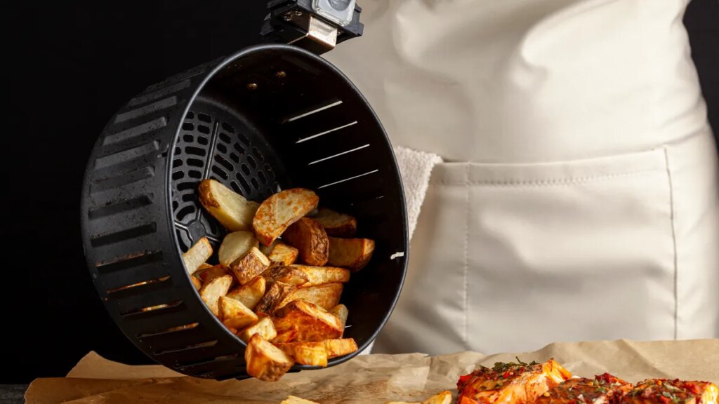 Person pouring cooked potatoes out of an air fryer