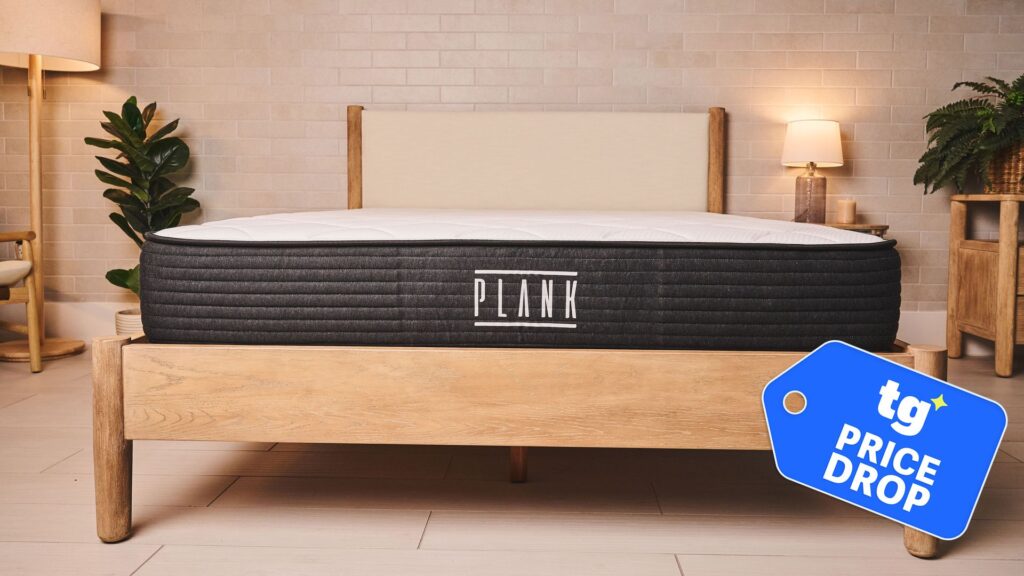 The Plank Firm mattress on a bed frame in a warmly lit bedroom. To the bottom, a Tom's Guide price drop deals badge